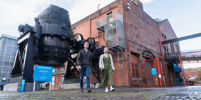 A couple walking in front of the bessemer converter at kelham island museum 