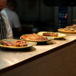 Rows of dishes on a counter top waiting to be served.