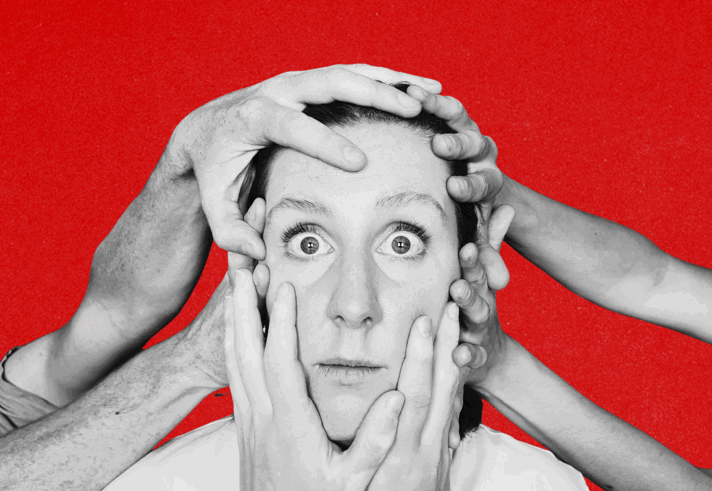 A close-up of a person's head with three pairs of hands pressed against it. The person is looking slightly startled and a little uncomfortable.