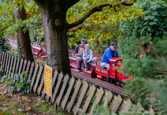 A family rides on a miniature steam train through a wooded area at the Abbeydale Miniature Railway in Sheffield.
