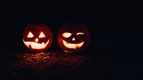 Two Halloween pumpkins glowing in the dark.