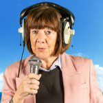 A person, wearing large headphones, talks into a microphone.
