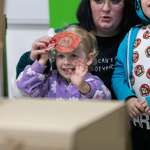 Two children and an adult looking at a video game.