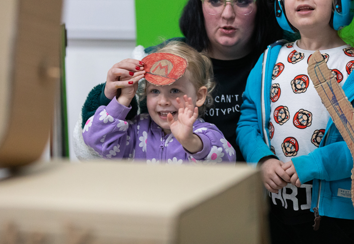 Two children and an adult looking at a video game.