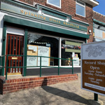 Exterior view of a brick-fronted record shop named “Spinning Discs Sheffield.” The shop has a green awning and large windows with posters and signs. 