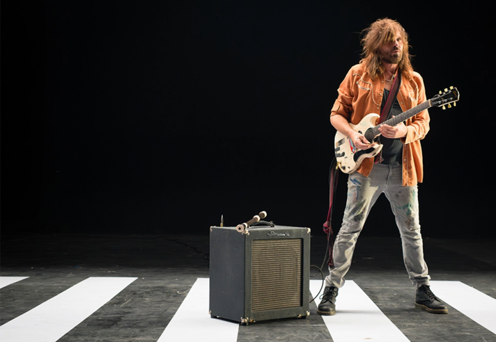 Evan Dando, of The Lemonheads, stood next to an amp, playing a white guitar.