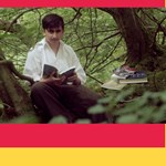 Still from Roma Film Screening of a young man sitting in a wood reading a book.