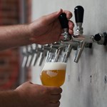 A pint being poured from pumps set into a wall.