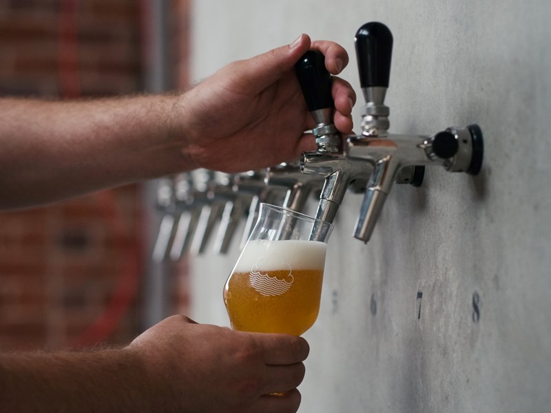 A pint being poured from pumps set into a wall.
