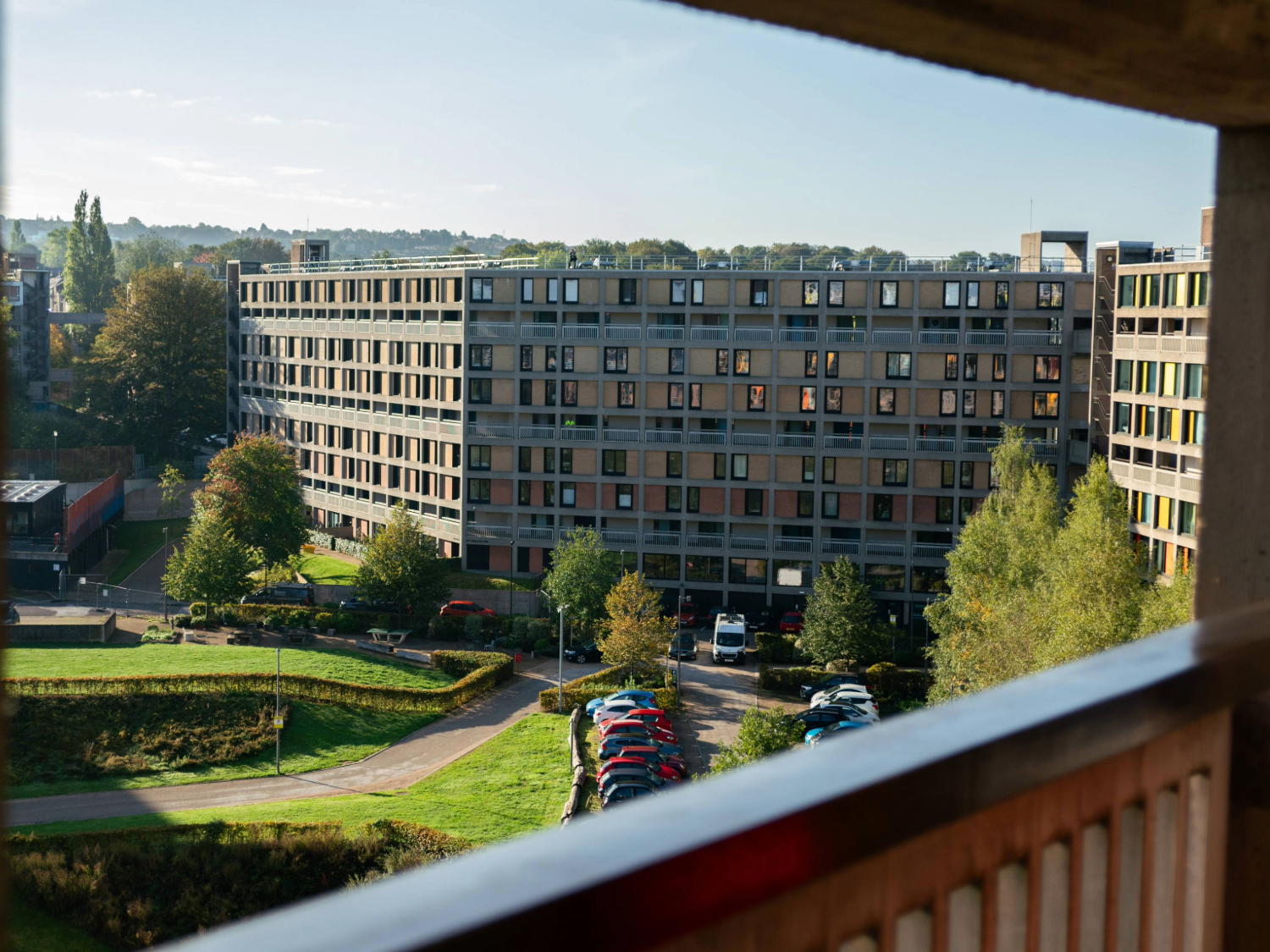 A view of a section of a brutalist high-rise apartment complex as viewed from a walkway in another section.