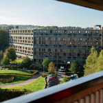 A view of a section of a brutalist high-rise apartment complex as viewed from a walkway in another section.