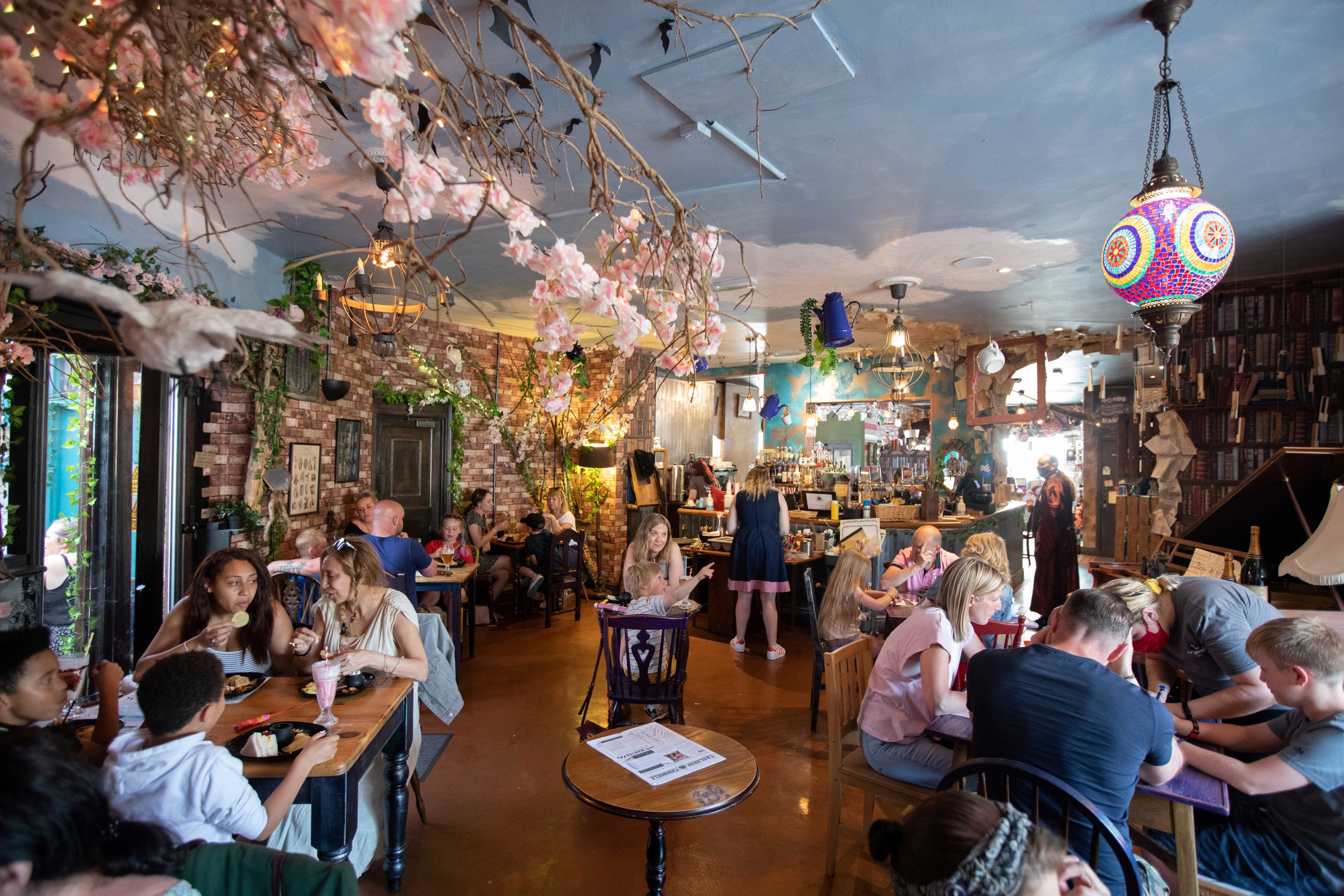 The interior of The Steel Cauldrons with people sat at tables eating, drinking, chatting and playing games.