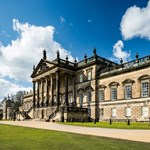 Side angle of the Wentworth Woodhouse viewed from the gardens, showing the imposing architecture against blue skies