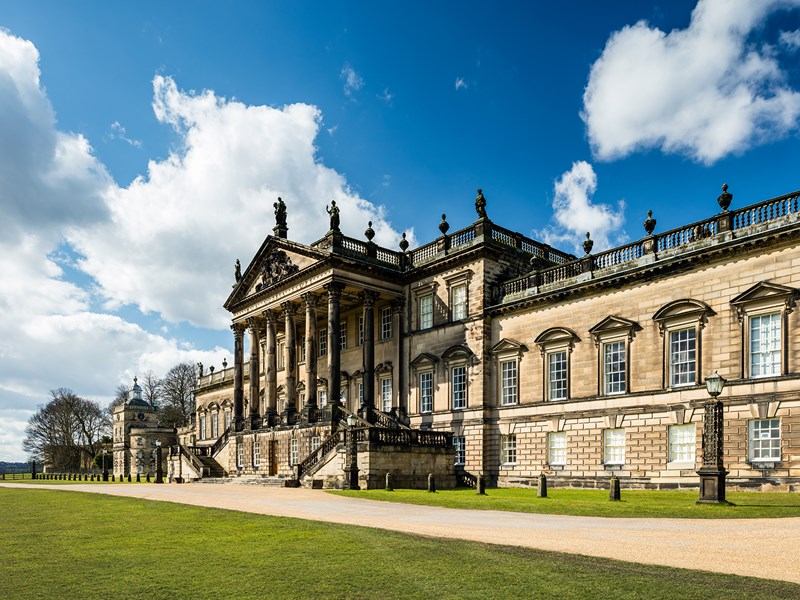 Side angle of the Wentworth Woodhouse viewed from the gardens, showing the imposing architecture against blue skies
