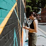 A street artist at work, paining a wall in Sheffield.