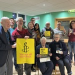 A group of people holding Amnesty International posters and signs.