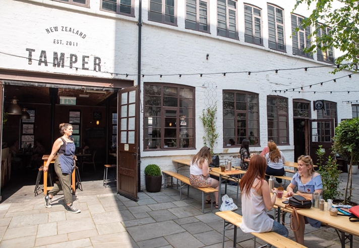 The courtyard at Tamper Coffee, with customers sat at tables.