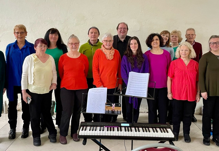 The members of Nether Edge Voices standing around a keyboard on a stand.