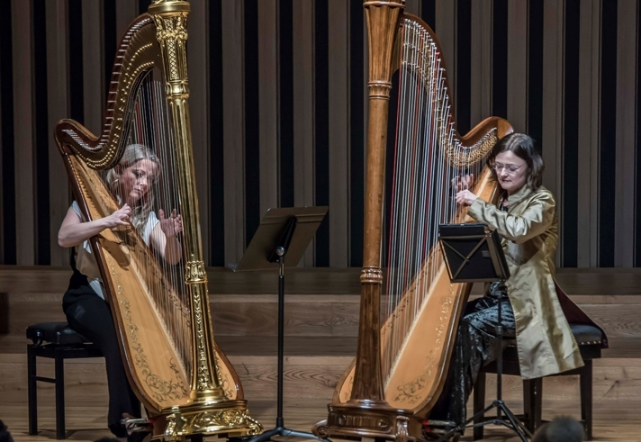 Two people playing harps on a stage.