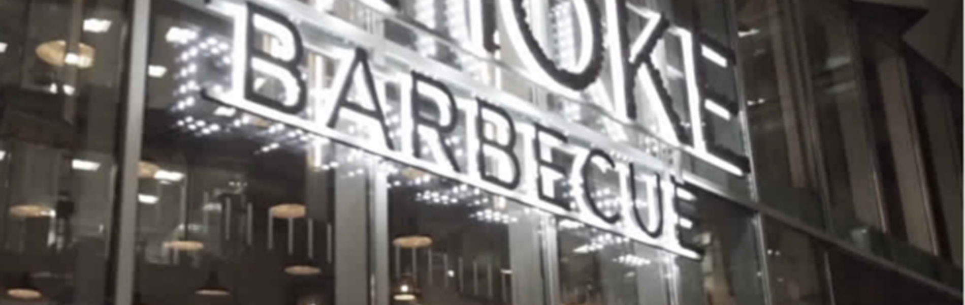 The Smoke BBQ sign lit up at night.