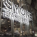 The Smoke BBQ sign lit up at night.