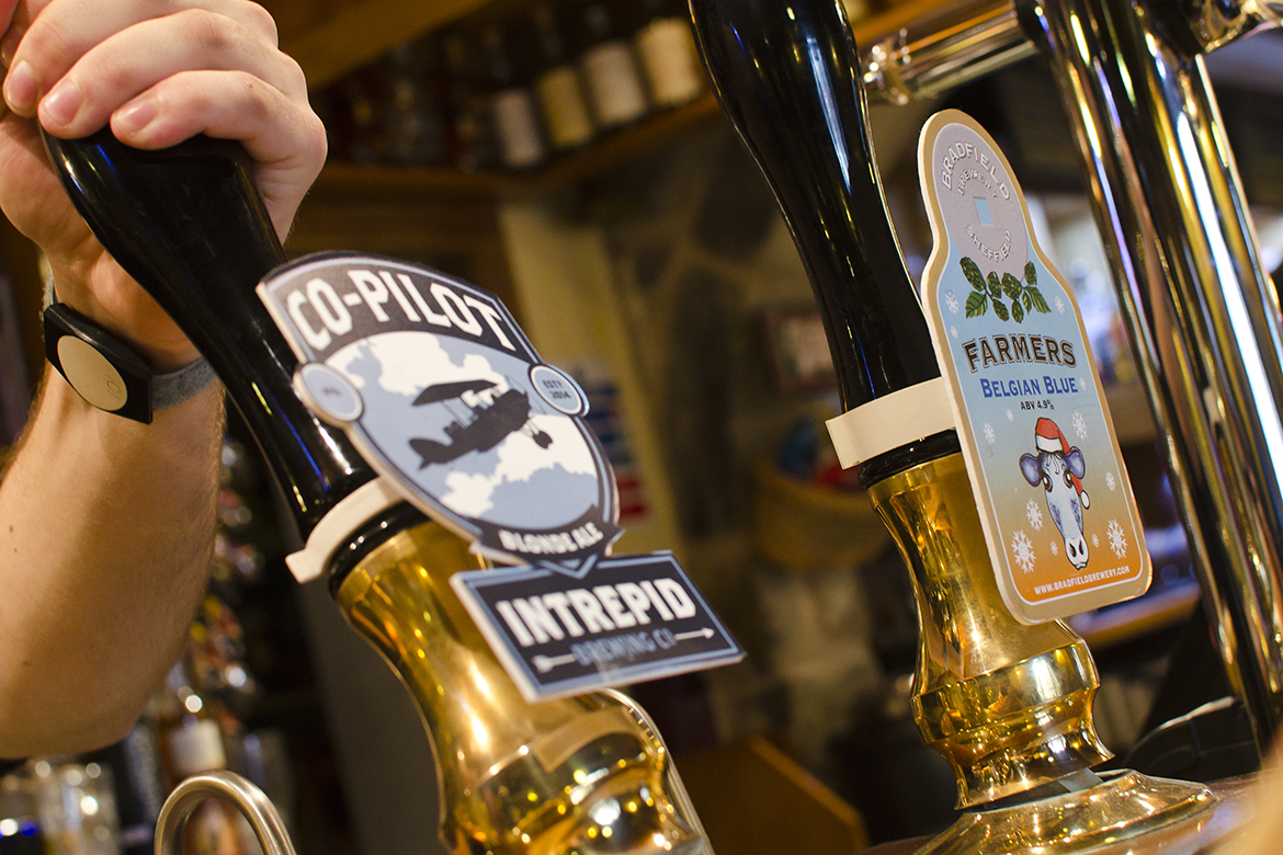 A hand pulling on a beer pump on a bar.