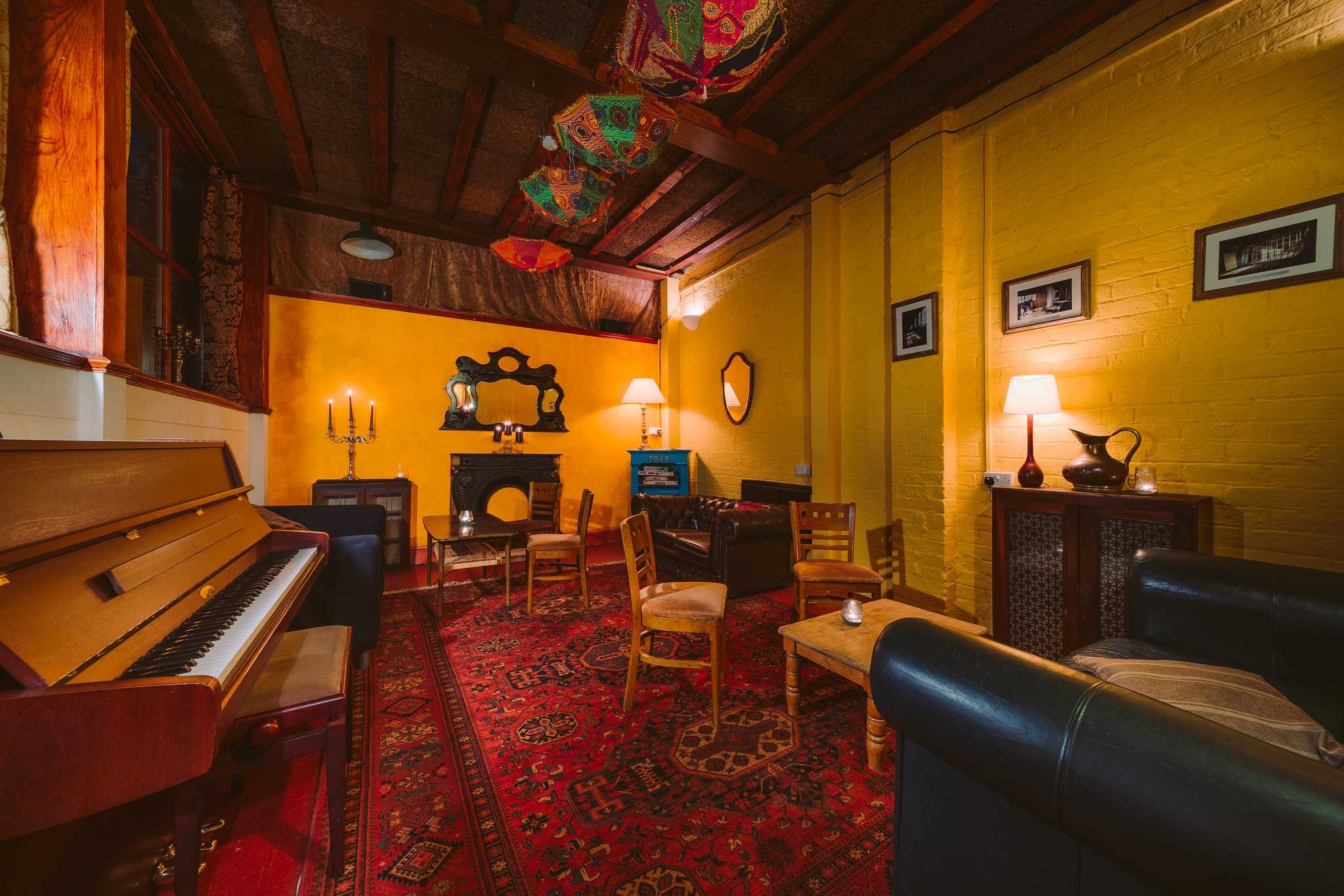 A room with a piano and a sofa and chairs around a low table.