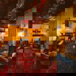 A room with a piano and a sofa and chairs around a low table.