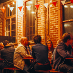 A group of people sat at tables outside, at night, having a night out. 