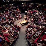 A packed house at the Crucible Theatre waits in anticipation for a classical concert to start. In the centre of the stage stands a grand piano.
