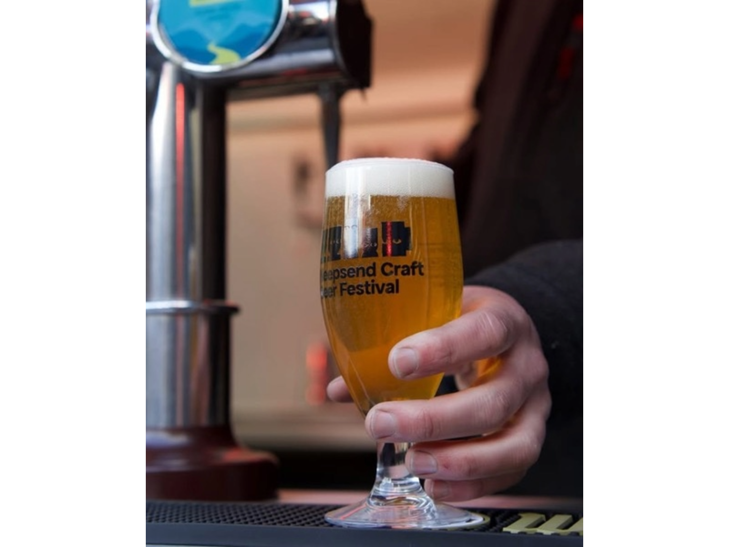 A glass of beer being poured from a beer pump.