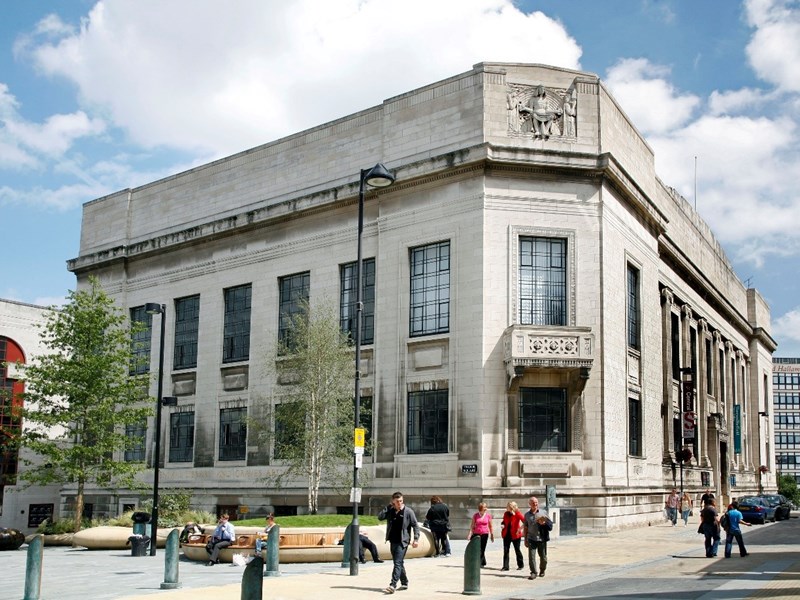 Exterior of Sheffield Central Library on a sunny day with people walking past