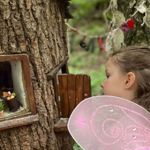 Children peering into a small door set into a tree.