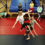 Young people practising tumbling and circus skills on safety mats.