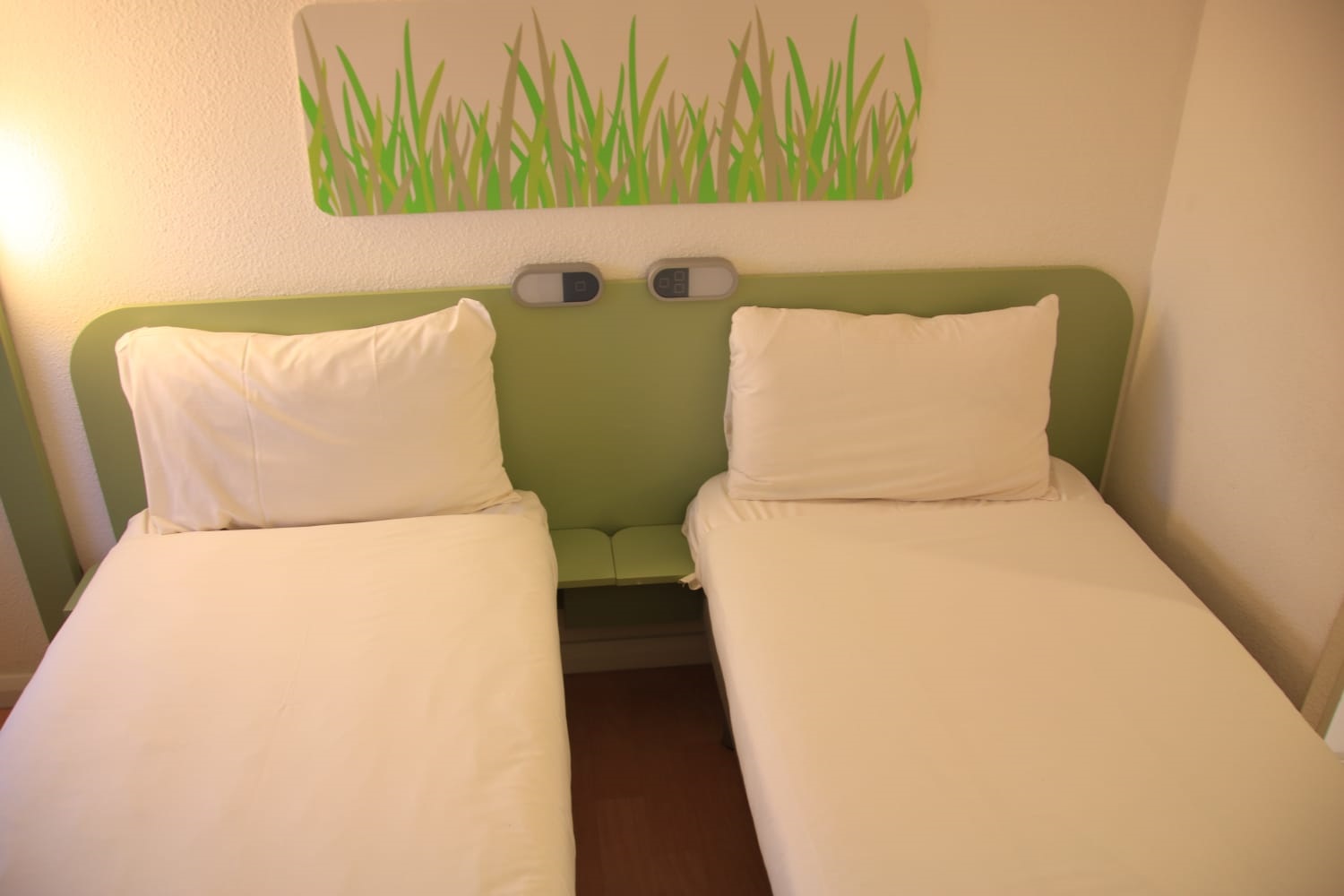 Bright bedroom featuring two neatly made single beds side by side.