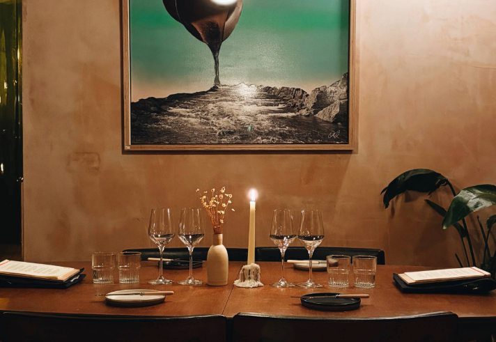 The interior of Restaurant Elm with a table laid out for two, under a large painting.