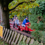 A family rides on a miniature steam train through a wooded area at the Abbeydale Miniature Railway in Sheffield.