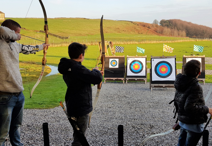 Three people doing archery at the Ringinglow Archery Target Sports Centre.