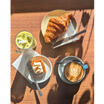 A wooden table, in the sun, with a coffee, delicious pastries and a smoothie at the Copper Pot Café.