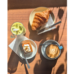 A wooden table, in the sun, with a coffee, delicious pastries and a smoothie at the Copper Pot Café.