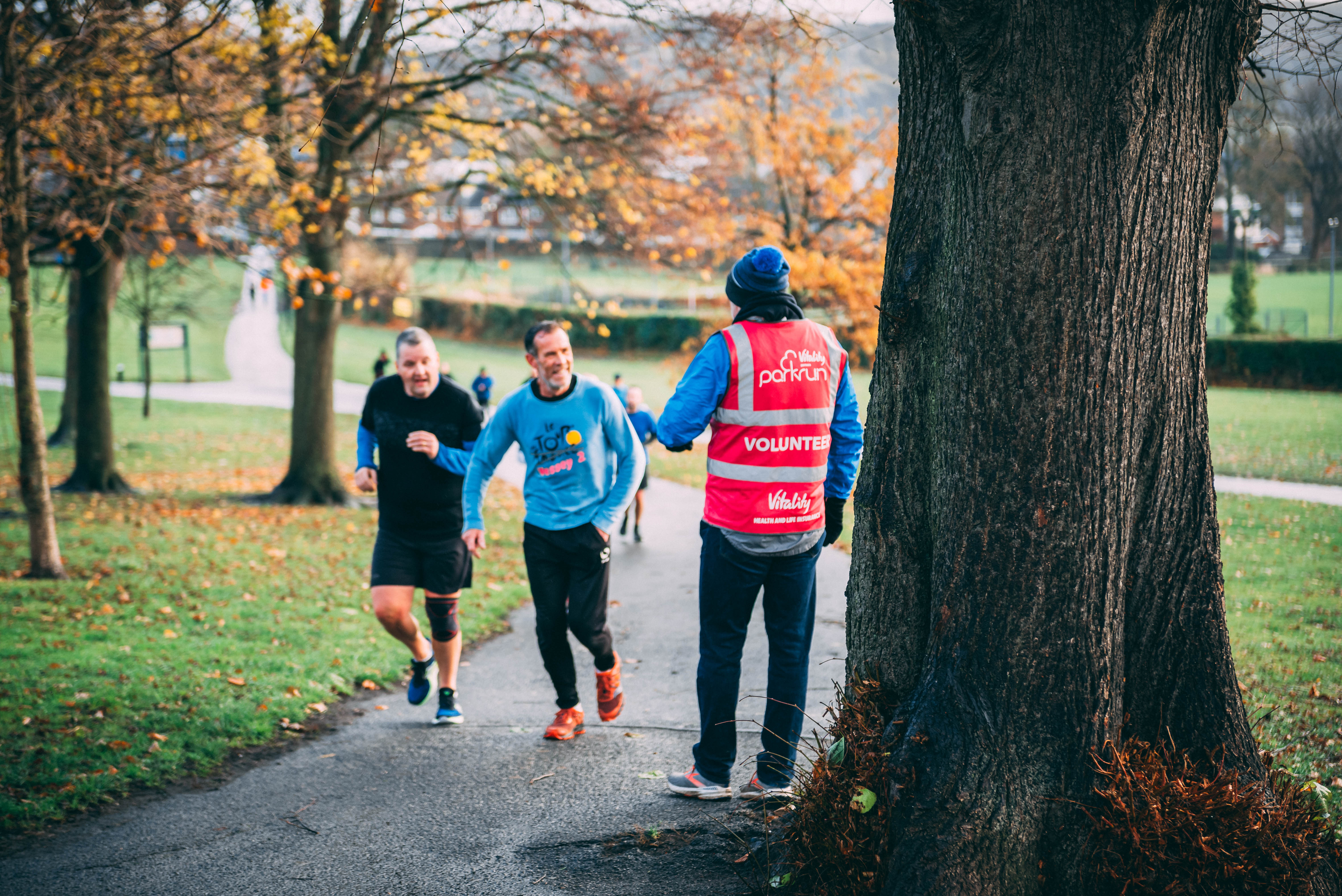 Two runners and a marshal at ParkRun in Hillsborough Park.