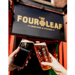 A pint of beer and a pint of Guinness being clinked together under The Four Leaf Irish Bar & Kitchen's sign. 
