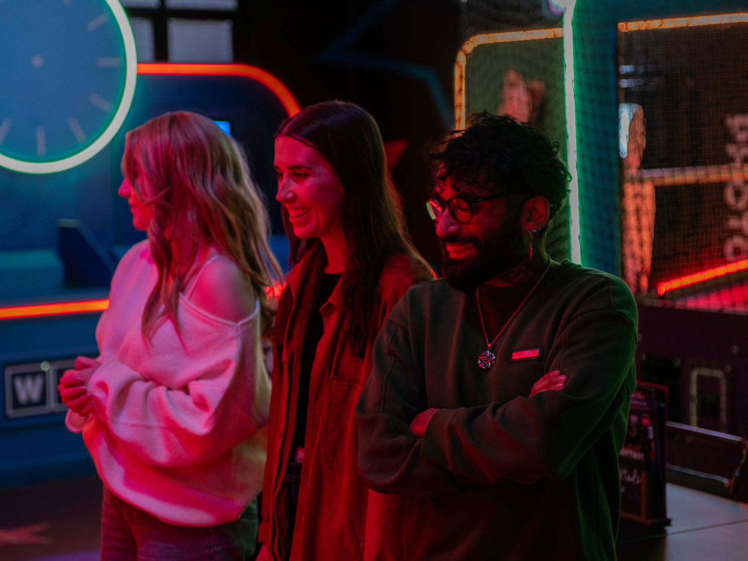 Three people at a neon-lit arcade.