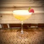 A yellow cocktail on a table.