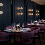 Mood-lit area of the restaurant with round tables set in a row.