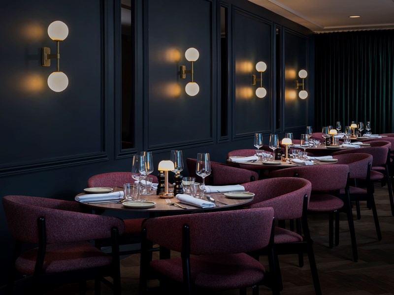 Mood-lit area of the restaurant with round tables set in a row.