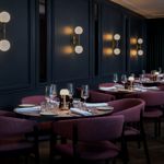Mood-lit area of the restaurant with round tables set in a row.