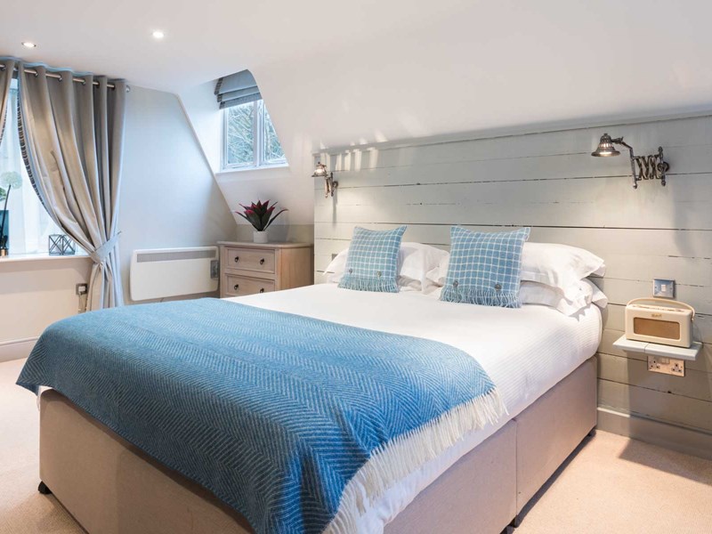 Elegant bedroom at The Florentine featuring a neatly made bed with a blue throw and contemporary décor.