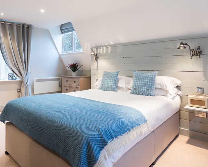 Elegant bedroom at The Florentine featuring a neatly made bed with a blue throw and contemporary décor.