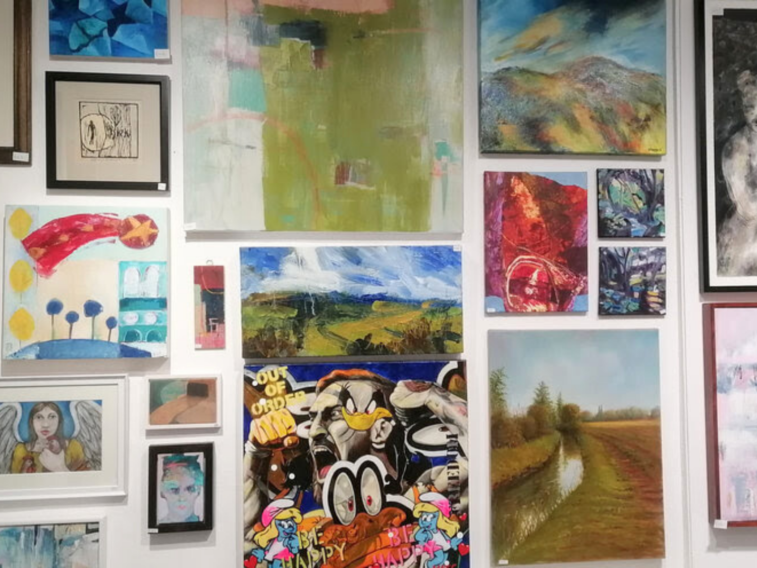 A gallery wall covered in paintings and artworks of all sizes.